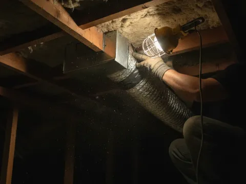Technician connecting ductwork during AC installation in Providence Village attic