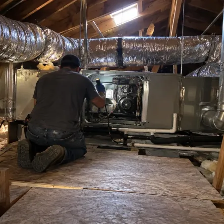 Technician working on a gas furnace and ductwork in the attic of a McKinney home